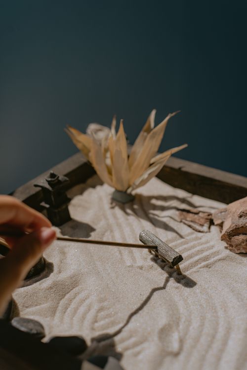 Free Close-up of a miniature Zen garden scene with sand patterns and small rakes. Stock Photo