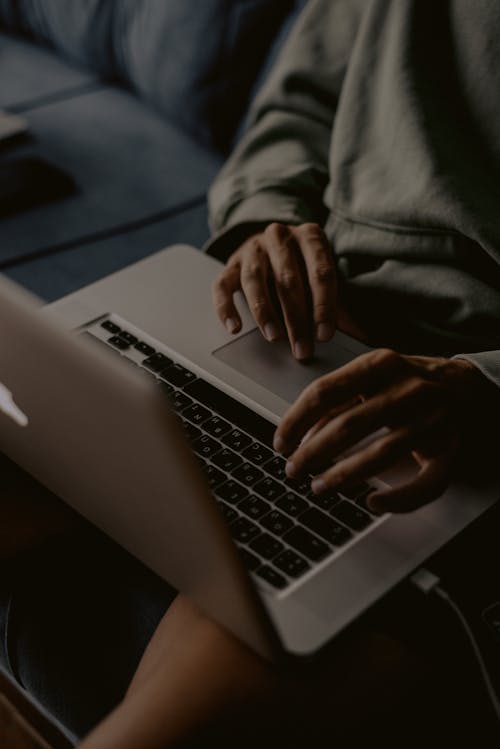 Person in a Green Long Sleeve Shirt Typing on a Laptop Keyboard