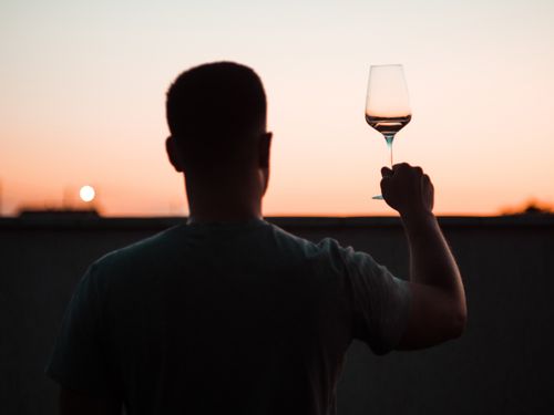 Free Silhouette of man raising a wine glass at a sunset outdoors. Stock Photo