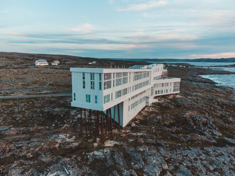 Aerial view of Fogo Island Inn on a rocky coast with ocean backdrop at dusk, Newfoundland.