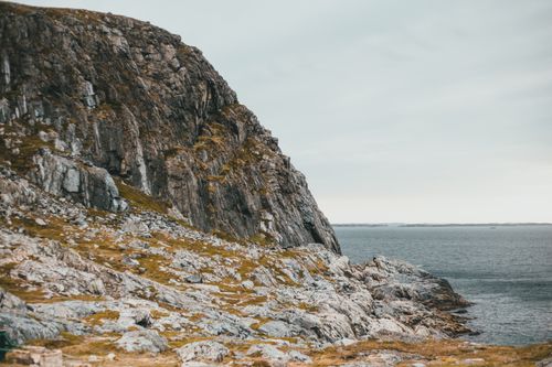 Free Scenic cliff by the sea with eroded rock formations and a serene ocean backdrop. Stock Photo