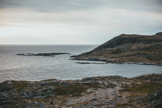 Dramatic seashore scene with rocky landscape and cloudy sky.