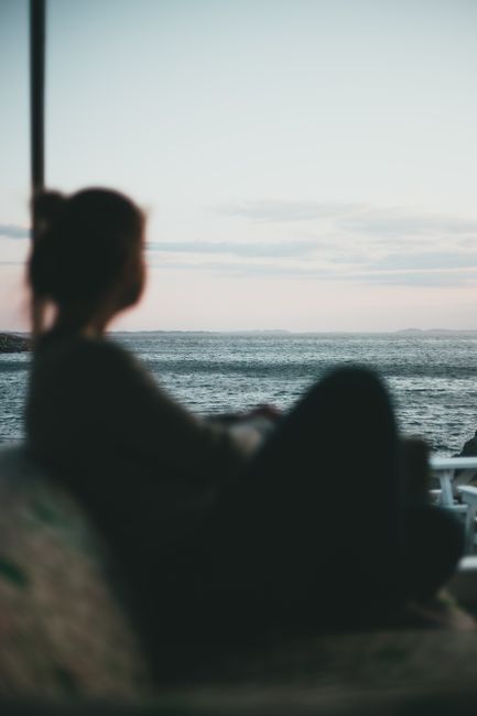 Silhouette of a woman gazing at the peaceful ocean during twilight, capturing serenity and reflection.