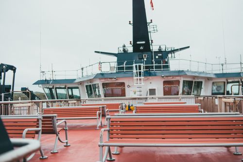 Free An empty ferry deck featuring rows of benches under an overcast sky, capturing the essence of maritime travel. Stock Photo