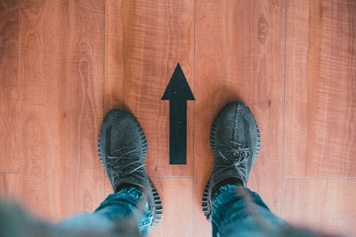 Photo of Person's Feet Near a Black Arrow