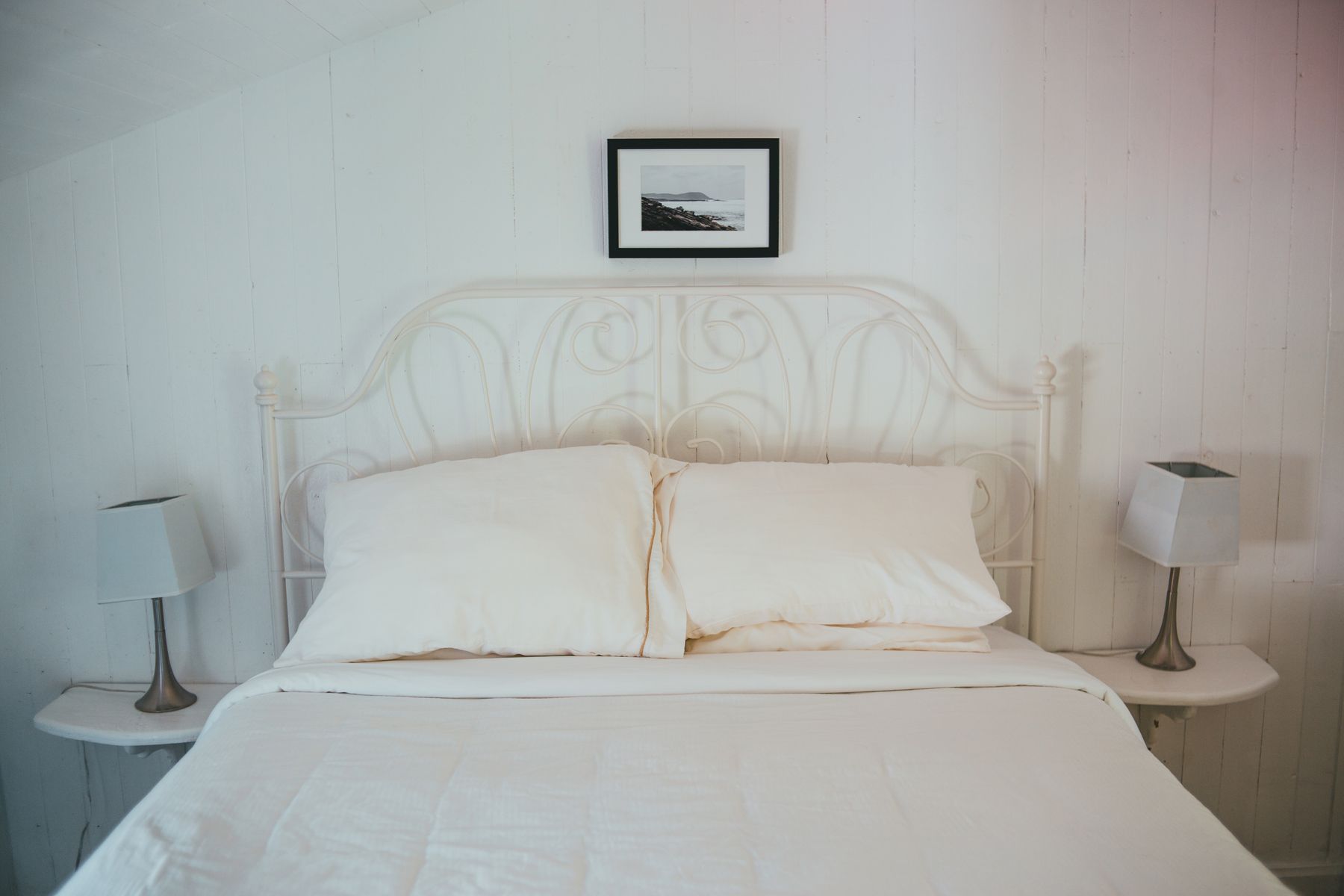 Contemporary pale bedroom with ivory bedding, cream walls and restrained timber details