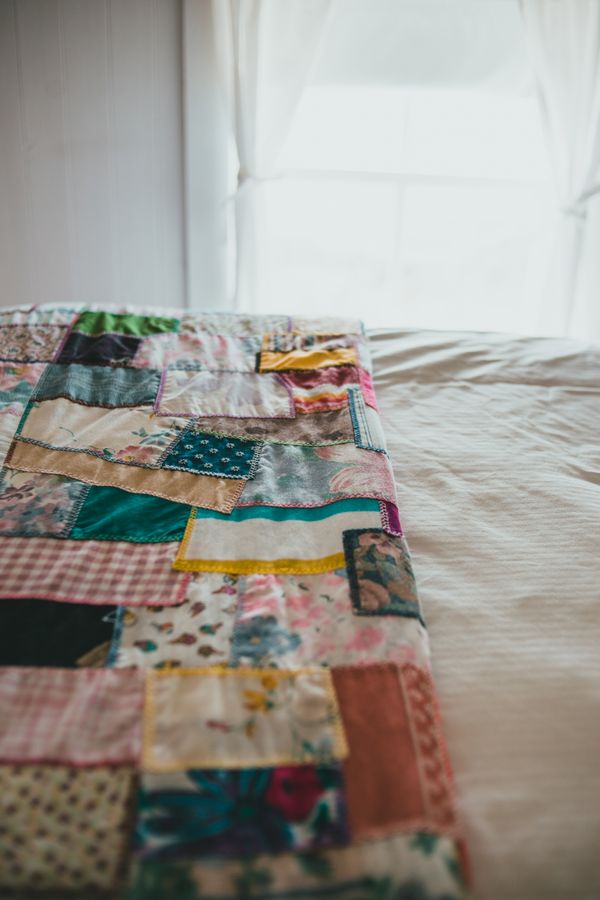 Beautiful handmade patchwork quilt draped over a bed in soft morning light, complete beginner quilting guide