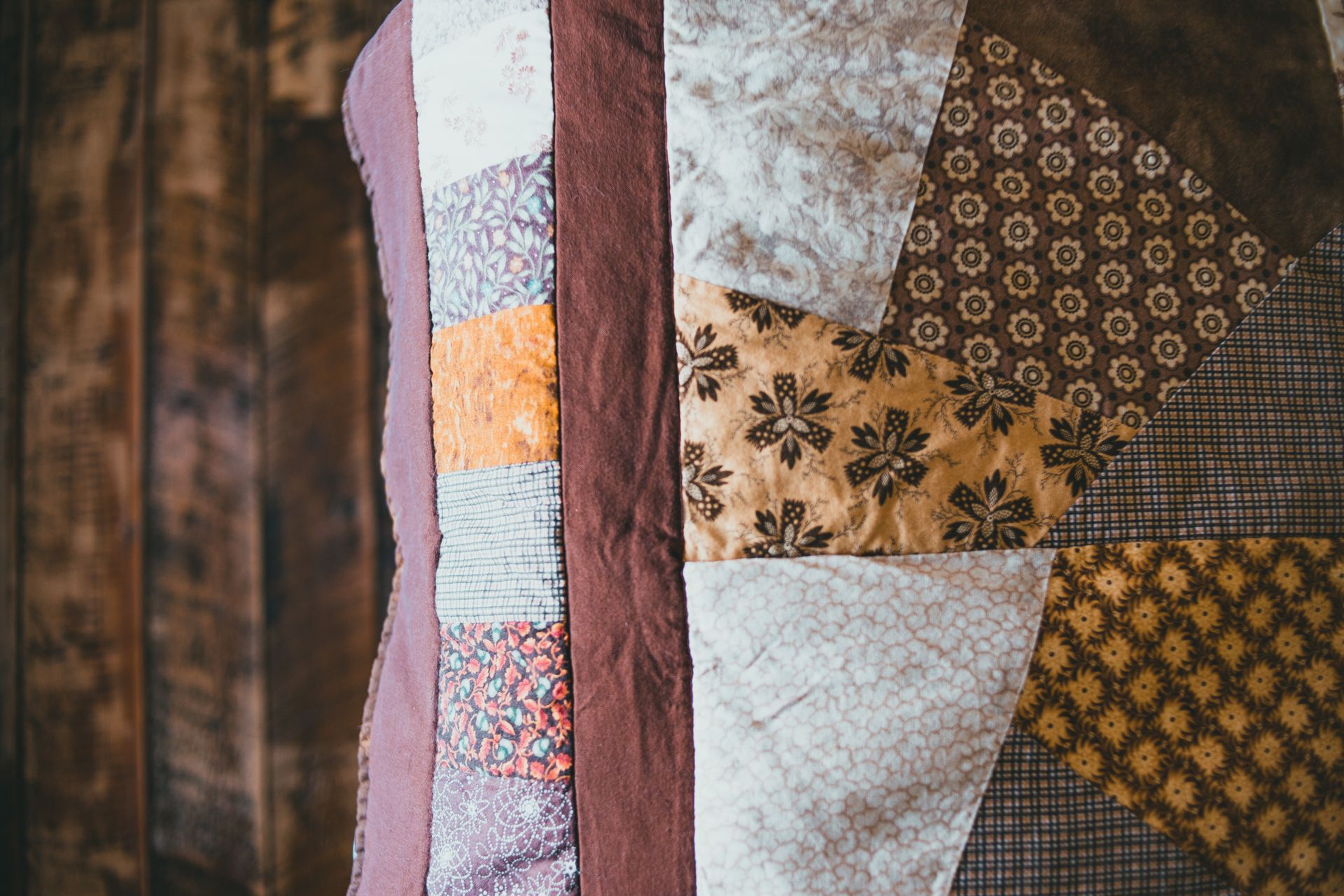 Close-up of a patchwork quilt with floral and geometric patterns in earthy tones.