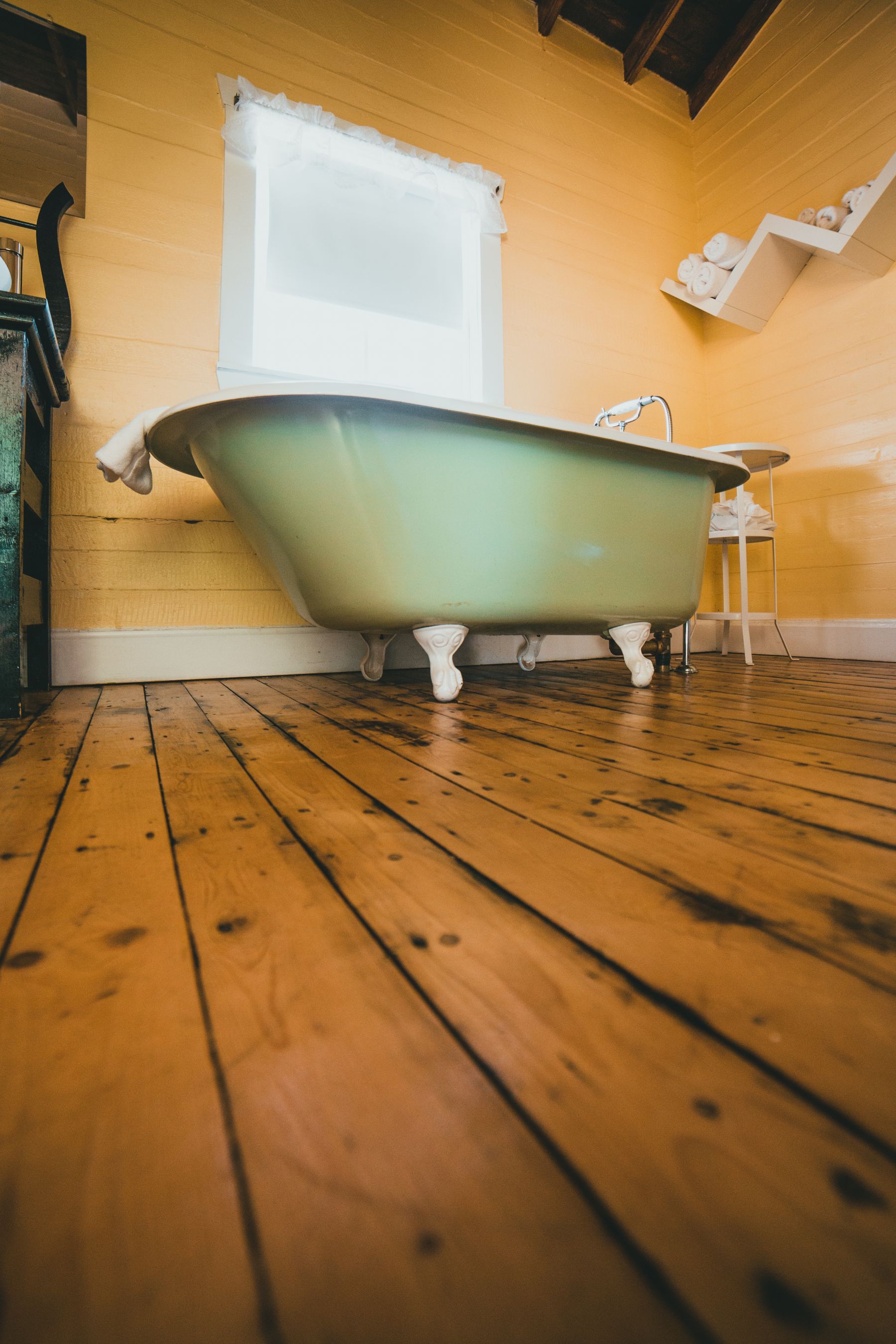 Classic clawfoot bath standing on warm wood flooring in a bright bathroom