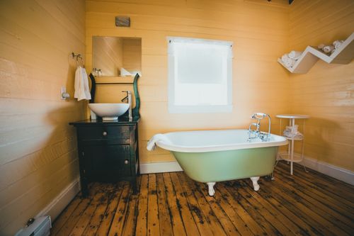 Free A charming rustic bathroom interior featuring a vintage clawfoot bathtub and wooden flooring. Stock Photo