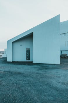 A sleek modern minimalist white concrete house with unique geometric design and minimal windows.