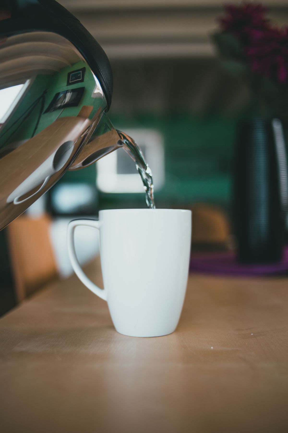Wasserkocher gießt heißes Wasser in eine Tasse