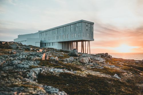 Free A striking modern structure on rocky terrain with a beautiful sunset backdrop. Stock Photo