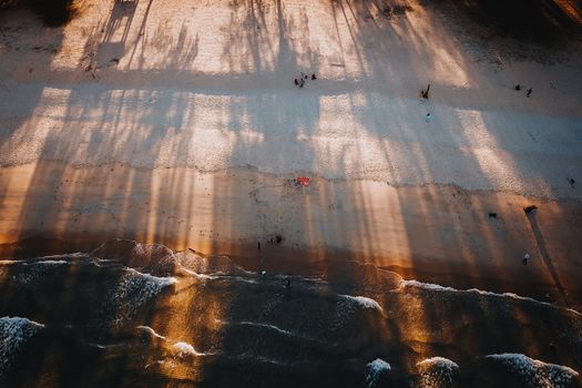 Stunning aerial photograph of Terengganu beach capturing shadows on sand and waves at sunset.