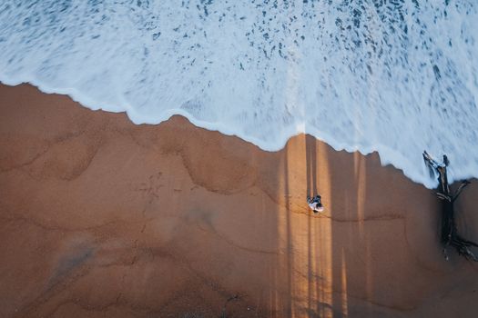 Drone shot of a solitary figure on a beach in Chukai, Malaysia, with waves and shadows enhancing the scene.