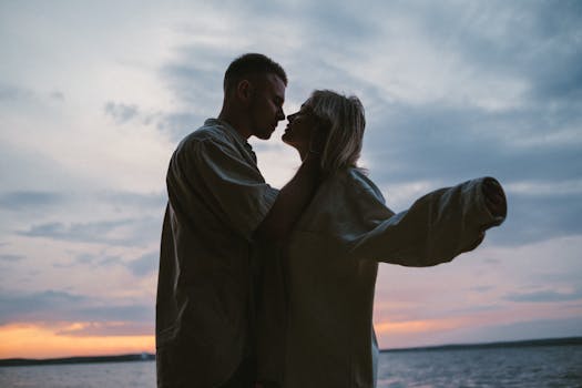 Silhouette of a loving couple embracing by the lake at sunset, capturing a romantic moment.