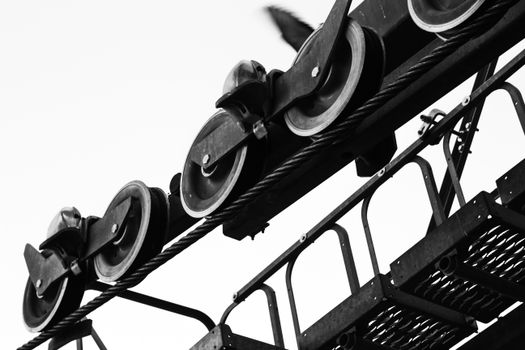 Black and white close-up of metal wheels and ropes in an industrial setting. Low angle perspective.