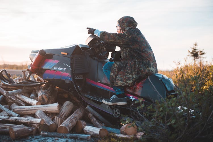 Man Sitting On Snowmobile And Pointing Direction