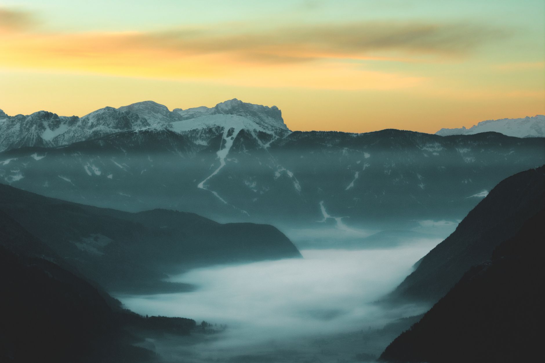 dramatic alpine mountains at sunrise with mist in the valley