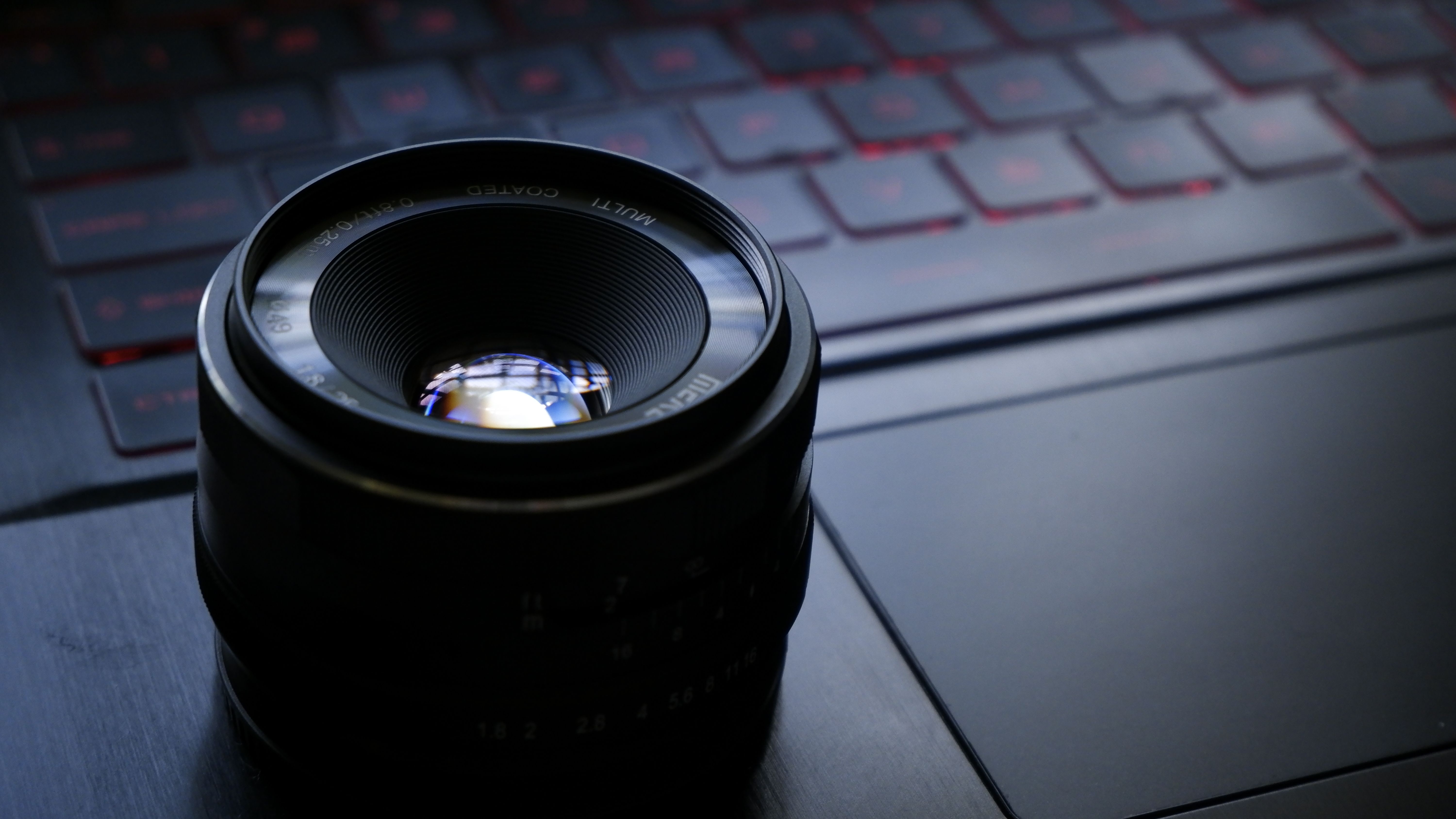 Photo of a camera lens placed on a laptop keyboard, highlighting photography equipment.