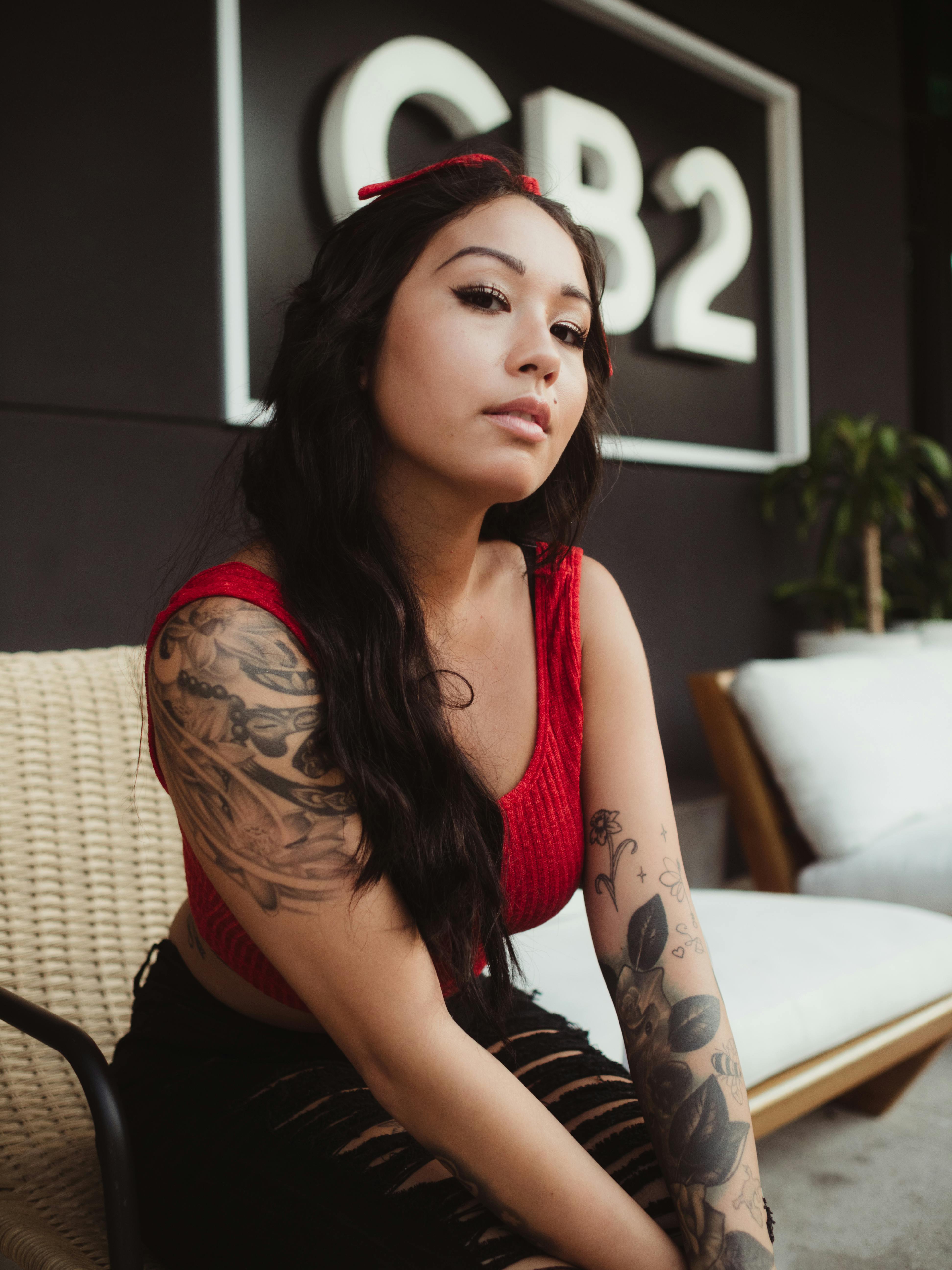 Beautiful Woman with an Arm Tattoo Sitting while Looking Away · Free Stock  Photo