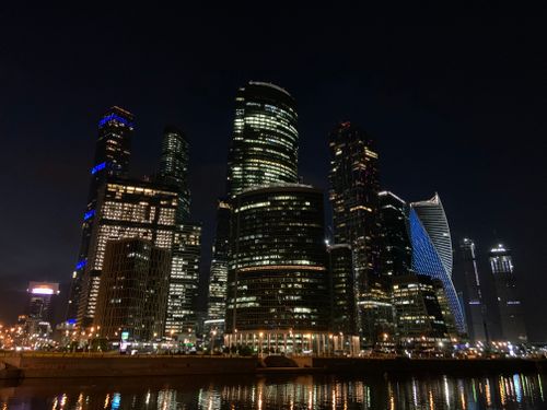 Free Vibrant city skyline at night with illuminated skyscrapers and reflections. Stock Photo