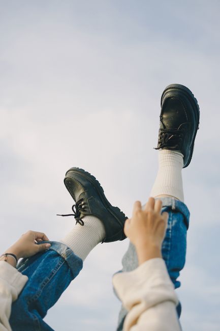 Relaxed outdoor shot of legs in jeans and leather shoes against the sky.