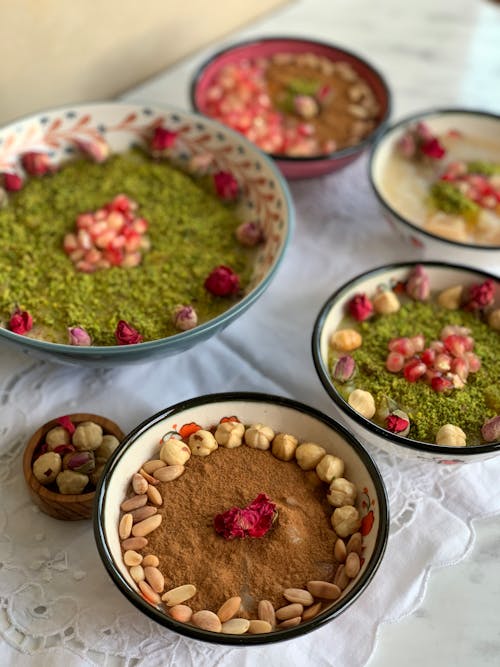 From above bowls of different meals decorated with various nuts placed on napkin