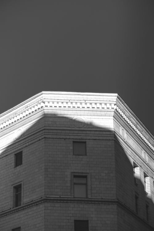 Free Elegant black and white photo of a building corner with intricate shadows on its facade. Stock Photo