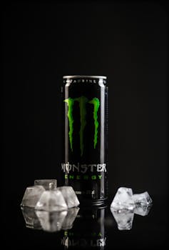 Close-up of a Monster Energy drink can surrounded by ice cubes, perfect for product advertising.