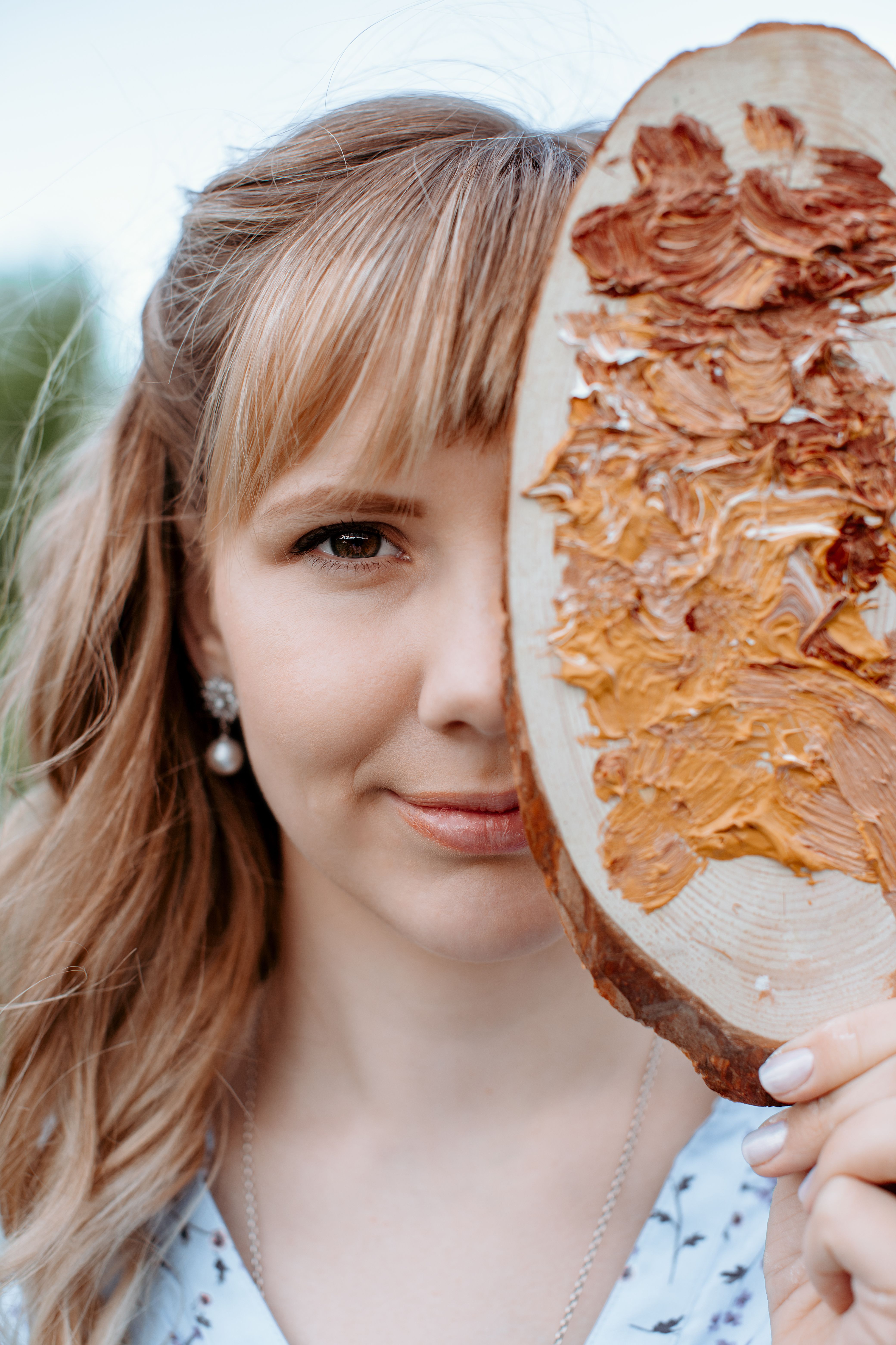Close-up portrait of a woman holding a paint palette outdoors. Creative and artistic expression.