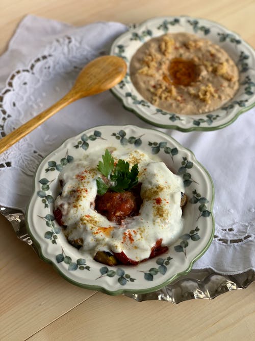 From above of appetizing meatballs with sauce placed on plate near porridge and wooden spoon on tray