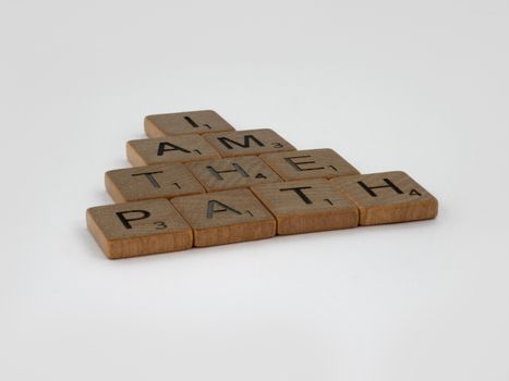 Scrabble tiles spelling out 'I Am The Path' on a white surface, inspiring message.