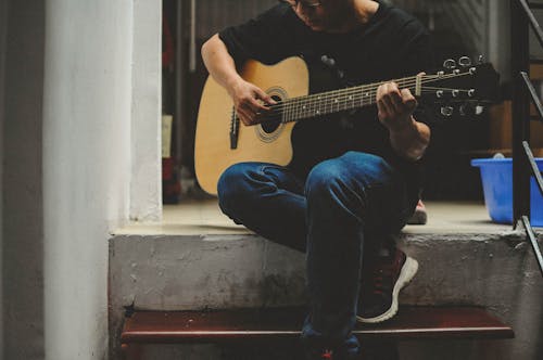 Free Man Playing Acoustic Guitar while Sitting Stock Photo