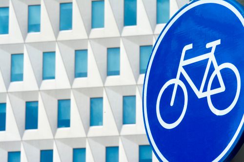 Free Blue bicycle sign in front of a modern geometric architectural building. Stock Photo