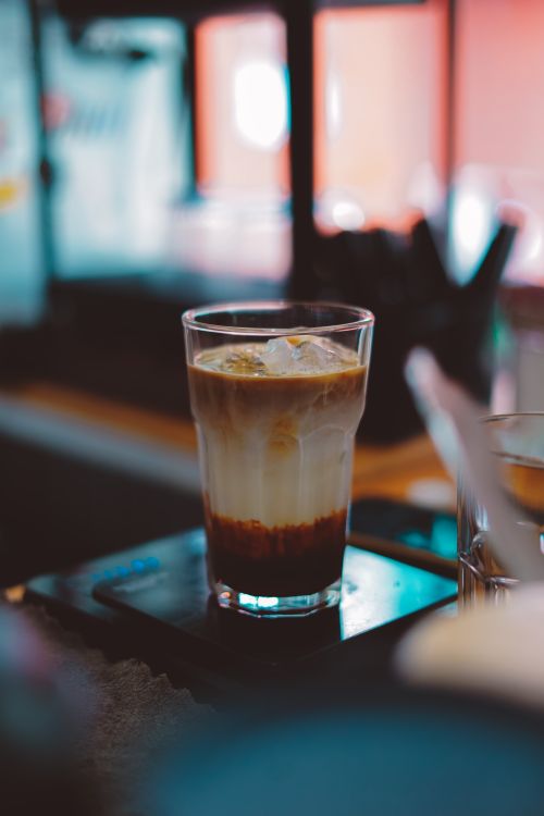 Free Aesthetic iced latte in a tall glass on a cafe counter. Perfect for beverage and cafe ambiance themes. Stock Photo