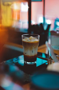 A refreshing iced coffee in a glass with a cozy cafe atmosphere and a colorful backdrop.