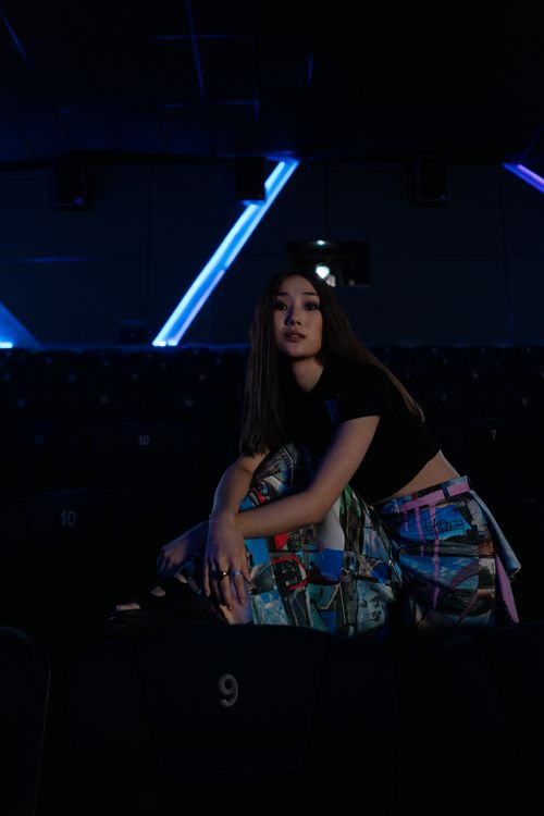 Free Stylish woman posing in a dimly lit cinema, embodying modern fashion. Stock Photo