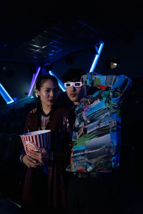 Free Young couple in a movie theater wearing 3D glasses, exuding a stylish and modern vibe. Stock Photo