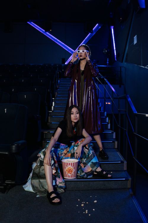 Free Stylish women in a cinema wearing 3D glasses and enjoying popcorn, capturing movie night vibes. Stock Photo