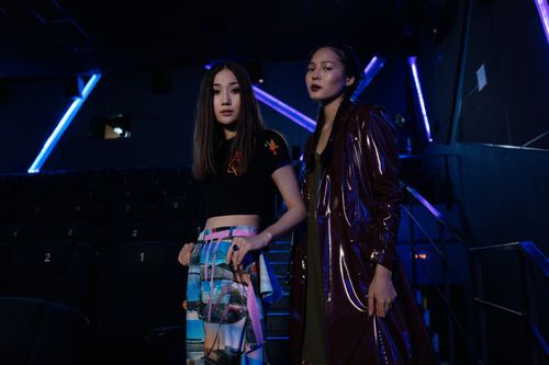Free Stylish Asian women posing confidently in a modern cinema environment with vibrant lighting. Stock Photo