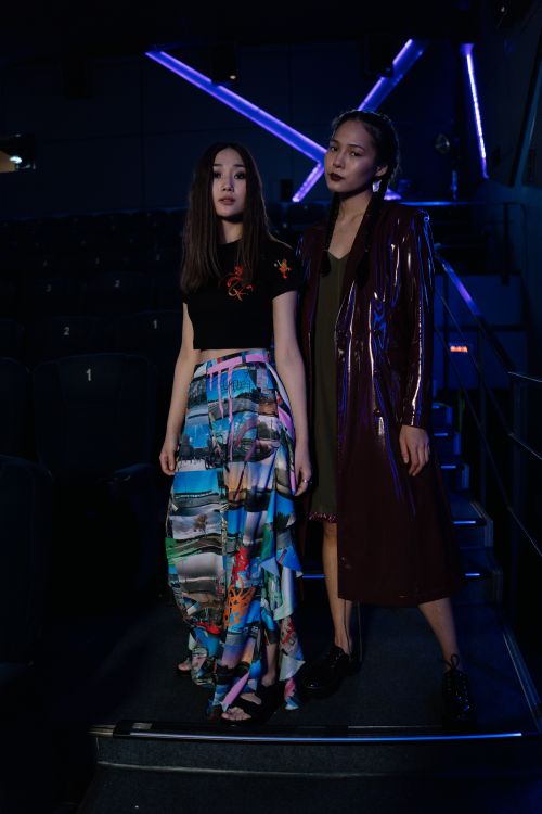 Free Two stylish asian women modeling modern fashion in a dimly lit cinema. Stock Photo