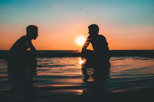 Free Two people silhouetted against a vibrant sunset at Laguna Beach, creating a peaceful and tranquil scene. Stock Photo