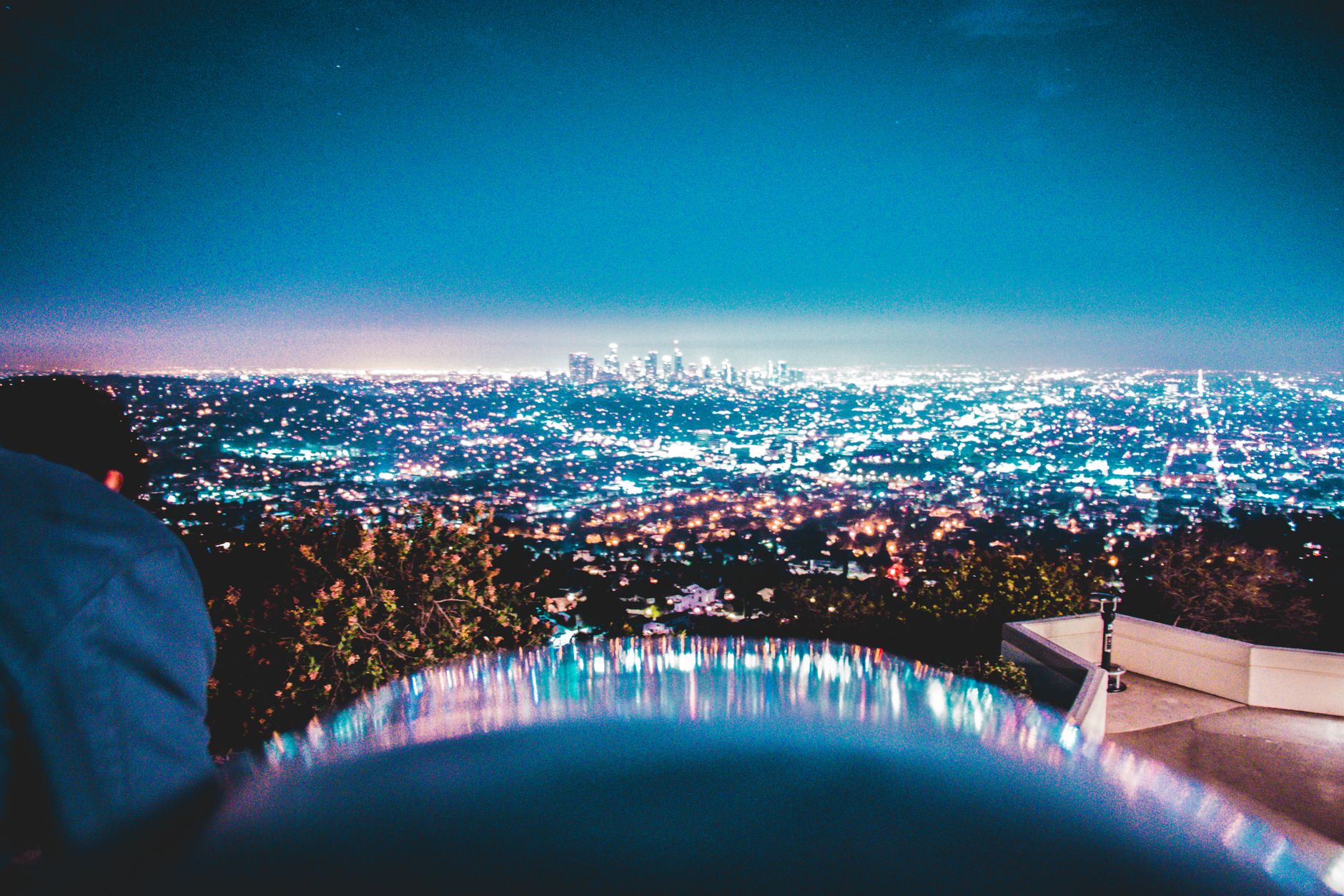 Night view of Los Angeles skyline with city lights from a hillside with a unique reflection.