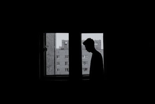 Silhouette of a Person Standing near the Windows