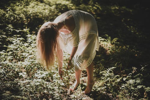 Woman Bending Down Barefoot in a Forest 