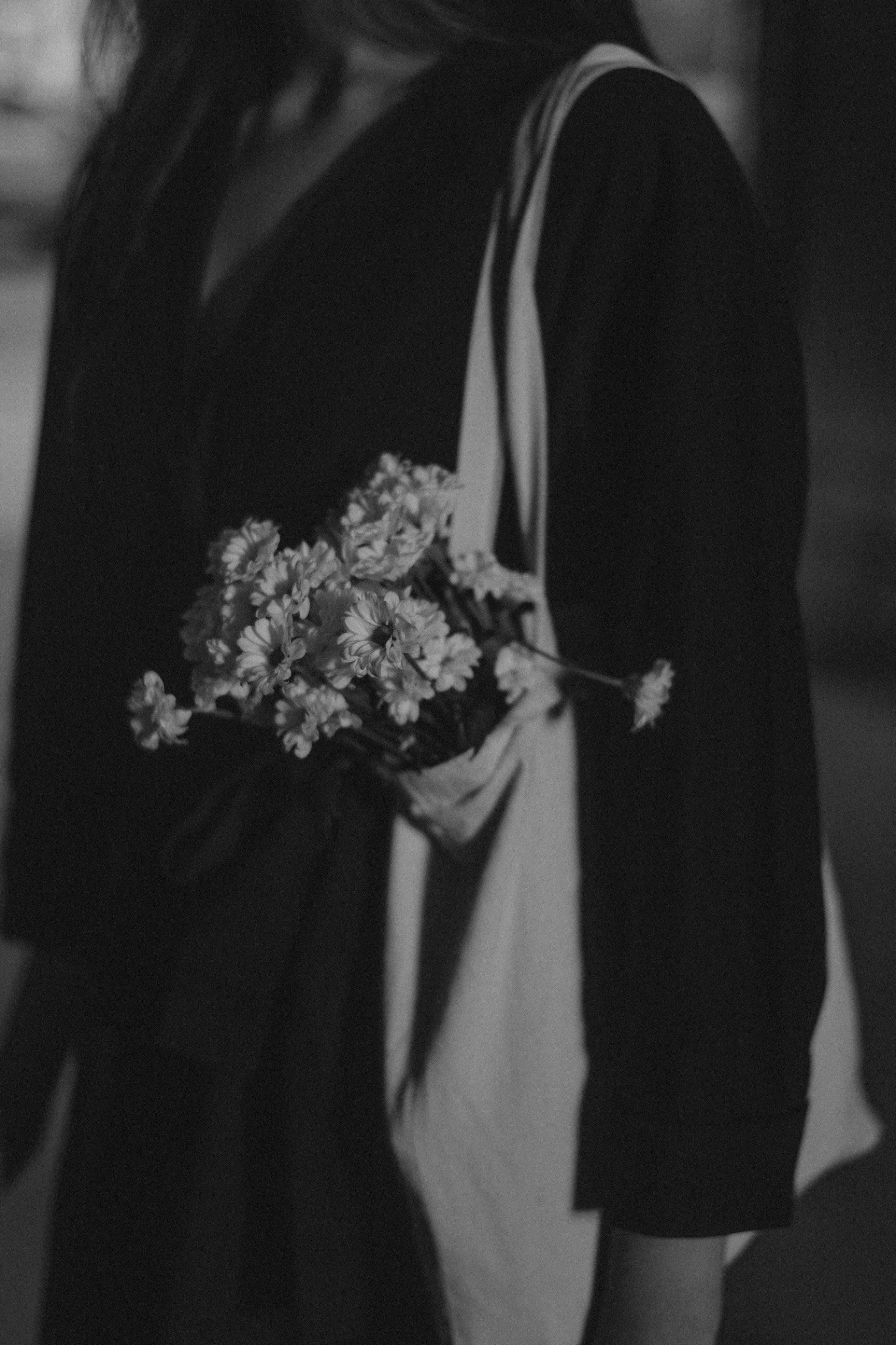 Artistic grayscale portrait of a woman with a shoulder bag and white flowers.