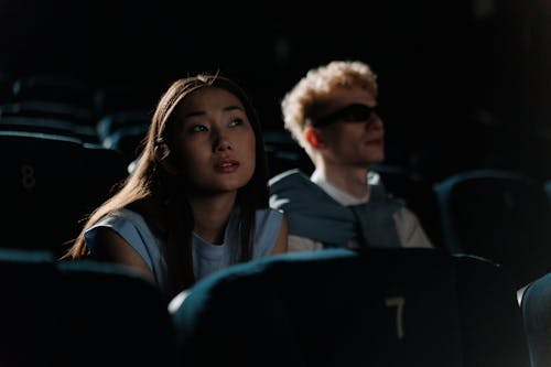 Woman in Blue Sleeveless Top Sitting Beside Man in Sunglasses