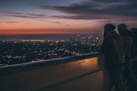 从阳台上俯瞰黄昏时的城市天际线，日落映衬着人们的身影