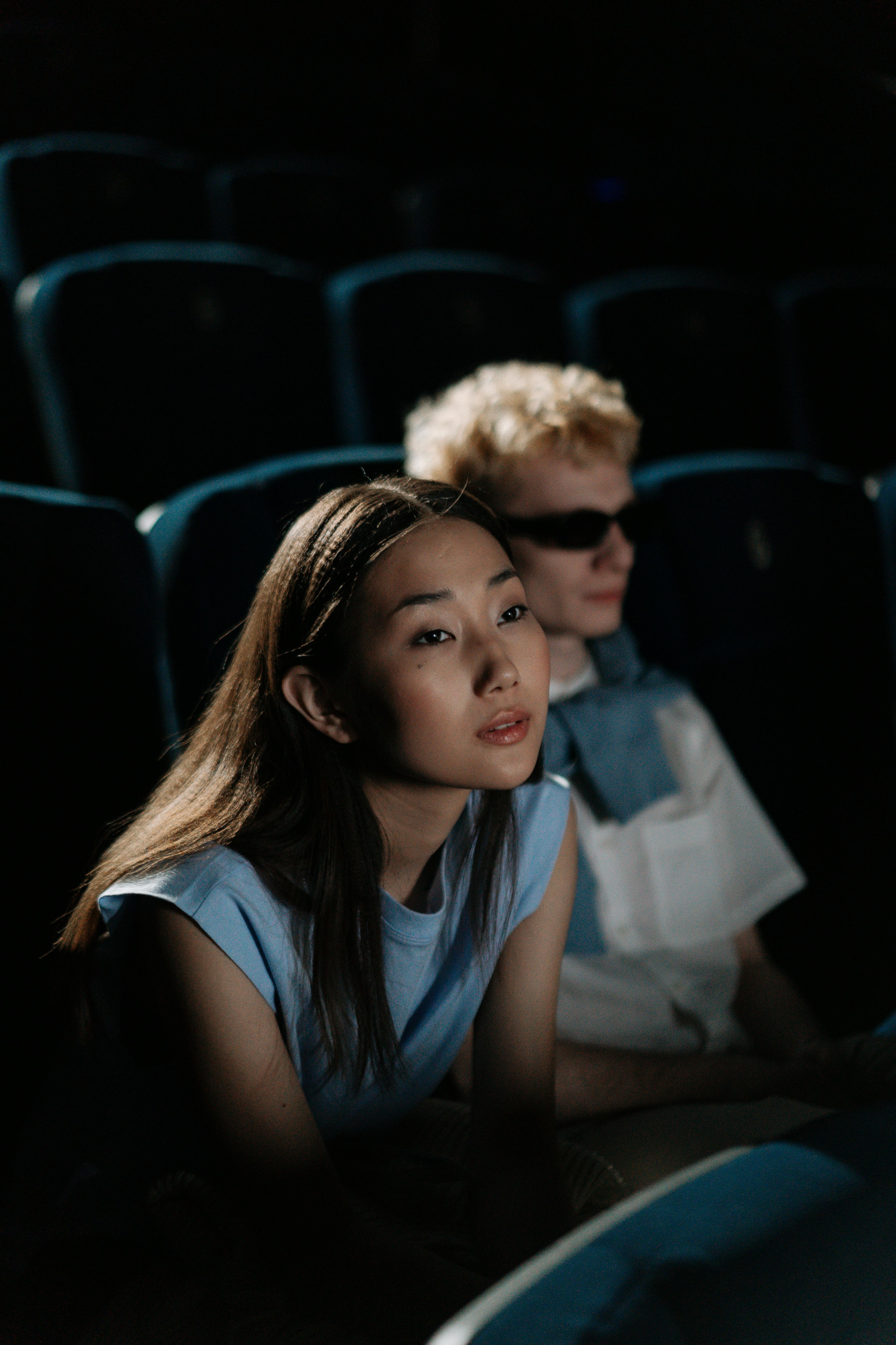 Free Two young adults watching a movie in a dark theater. Intently focused and immersed. Stock Photo